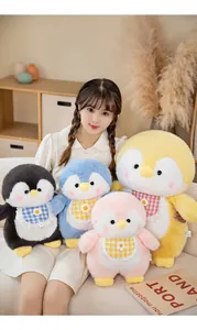 A variety of colorful cute penguin plush dolls being held by a model in a cozy indoor setting