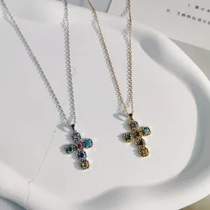 Close-up of gold and silver cross pendants with vibrant colorful zircon stones