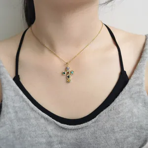 Elegant gold cross pendant necklace with colorful zircons shown on a model's neck