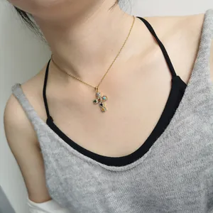 Close-up of a gold necklace featuring a colorful zircon-encrusted cross pendant.