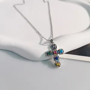 Detailed view of a silver necklace featuring a cross pendant with colorful zircon stones