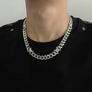 Detailed close-up view of a silver barbed wire Cuban chain necklace worn by a male model