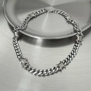 Detail of a silver barbed wire Cuban link chain necklace for men in hip-hop style.
