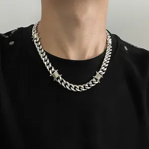 Close-up of silver barbed wire Cuban chain necklace for men on a black t-shirt