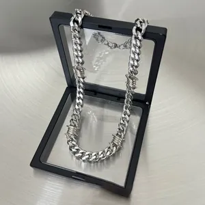 Macro detail of silver cuban link necklace with barbed wire thorns in display box