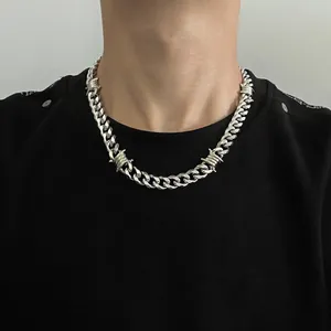 Detailed close-up of a silver thorn Cuban link chain necklace on a male model's neck