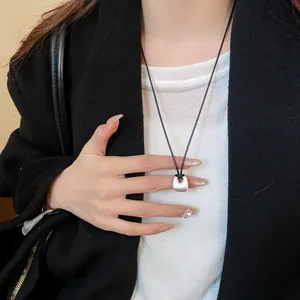 Primo piano di una collana con ciondolo quadrato in argento minimalista indossata da una modella