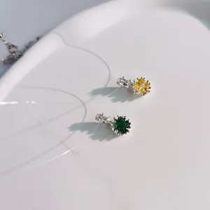 Close-up of yellow and green star-shaped crystal pendants on a minimalist white surface