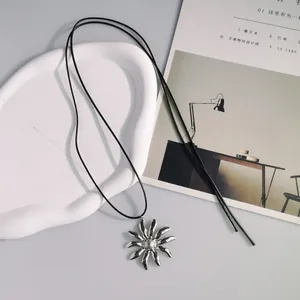 Dettaglio di una collana lunga in pelle stile etnico vintage con ciondolo a fiore.