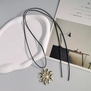 Vista dettagliata di una collana a corda lunga vintage con ciondolo a fiore d'oro pieghettato