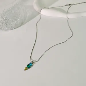 Detailansicht einer silbernen Halskette mit gelbem, grünem und blauem Edelsteinanhänger.