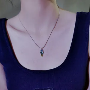 Nahaufnahme einer minimalistischen Titanstahlkette mit drei farbigen Steinanhängern.