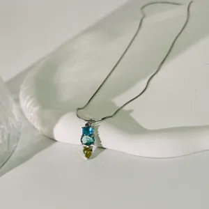 Nahaufnahme einer minimalistischen Halskette mit bunten blau-grünen Edelsteinanhängern