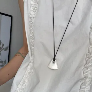 Primo piano del ciondolo a cuore in argento opaco irregolare su una collana di cordoncino nero