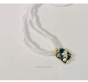 Detailaufnahme einer Vintage-Perlenkette mit einem eleganten blauen Emaille-Blumenanhänger
