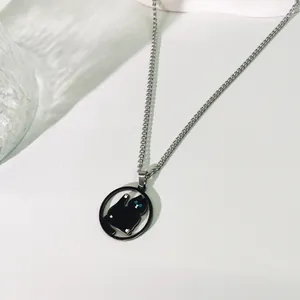 Primer plano de un collar con colgante de gato negro y ojos azules, cadena plateada.