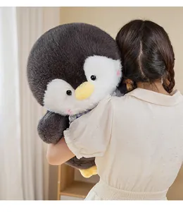 Large soft plush penguin doll held by a person showing its fluffy texture and size