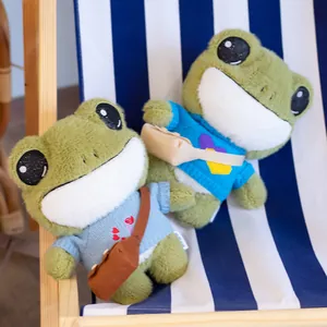 Cute frog plush toys wearing knitted sweaters and small bags on a blue striped chair