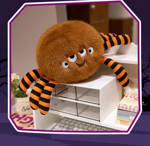 Funny Halloween monster spider plush toy with orange striped legs on a white desk.