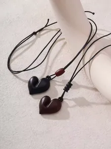 Détail de deux pendentifs cœur 3D minimalistes sur des colliers à cordon réglables noirs.