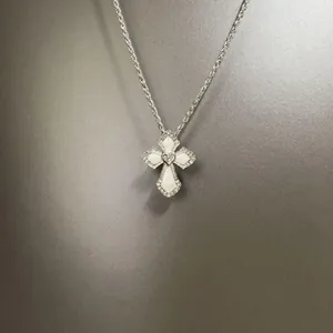 Vista dettagliata di una collana a croce hip-hop d'argento con inserto in conchiglia e cristalli