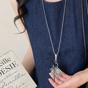 Detailed view of titanium steel sweater chain with metallic mesh pendant and black bow.