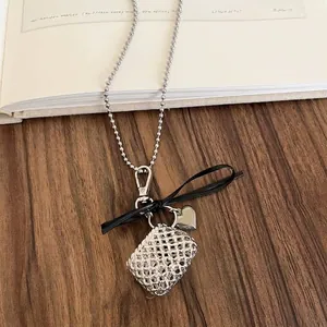Detail of silver woven bag pendant necklace with black ribbon bow and heart charm