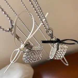 Detail shot of silver woven basket pendants on ball chains with ribbon bows