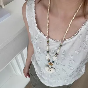 Vista detallada de un colgante de corazón de piedra de lava crema en un collar largo boho