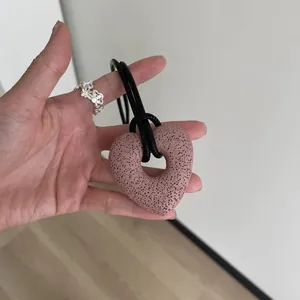 Vista detallada del collar con colgante de corazón de piedra volcánica en mano