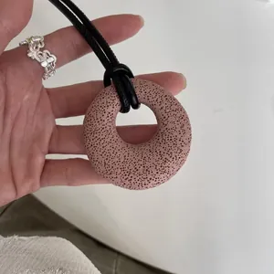 Primer plano de colgante circular de piedra de lava en cordón de cuero negro