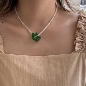Primo piano di collana di perle fatta a mano con ciondolo a fiore in vetro verde al collo