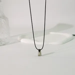 Nahaufnahme eines geometrischen Prismenanhängers an einer schwarzen Kordelkette
