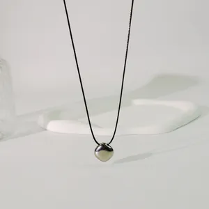 Nahaufnahme eines metallischen geometrischen Anhängers an einer minimalistischen Wachsschnur