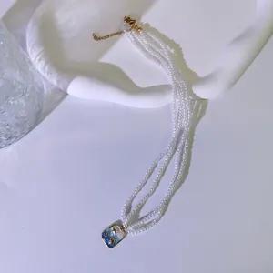 Detaillierte Nahaufnahme einer dreireihigen Perlenkette mit Ozean-Emaille-Anhänger.