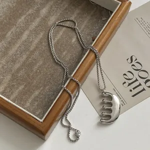 Detailed close-up of the unique silver-colored comb pendant with a high-polished metallic finish