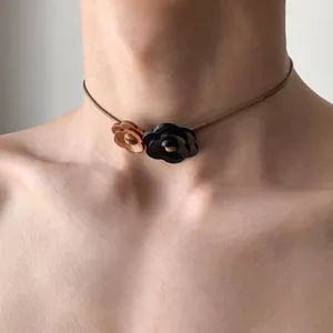 Close-up detail of a minimalist wooden flower choker on a vintage leather cord