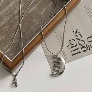 Detailed macro shot of a silver stainless steel comb pendant necklace on a minimalist tray