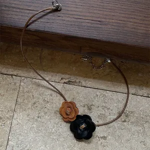 Detail view of a vintage wooden flower choker necklace with a brown leather cord