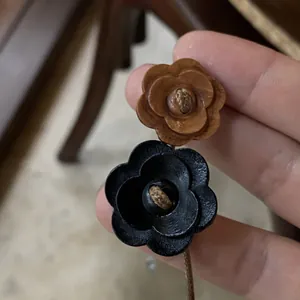 Close-up of retro wooden flower charms on a minimalist leather cord choker necklace