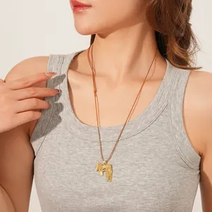 Nahaufnahme einer goldenen Vintage-Halskette mit Pferdeanhänger und Quasten am Modell