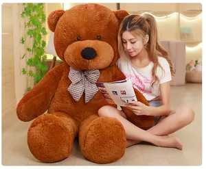 Giant brown teddy bear plush toy shown with a female model to demonstrate its large size.