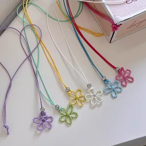 Primo piano di collane con ciondolo a fiore traforato in sei vivaci colori dopamina