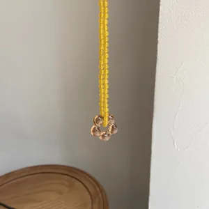 Primo piano di una collana di perline gialle con un ciondolo a forma di fiore in vetro