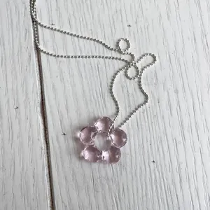 Dettaglio ravvicinato di una delicata collana con pendente a fiore in vetro rosa e catena