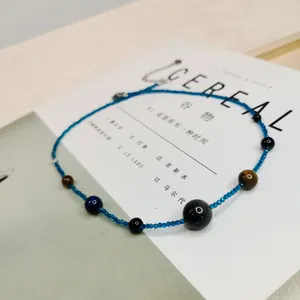 Nahaufnahme einer blauen Vintage-Perlenkette mit Tigerauge-Steinen auf Magazin