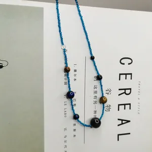 Nahaufnahme einer Vintage-Perlenkette mit blauen Perlen und Tigerauge-Steinen auf Magazin-Hintergrund