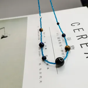 Detailaufnahme einer Vintage-Halskette mit blauen Perlen und Tigerauge-Steinen auf Buch