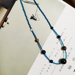 Detailansicht einer Retro-Tigerauge-Halskette mit kleinen blauen Kristallperlen.