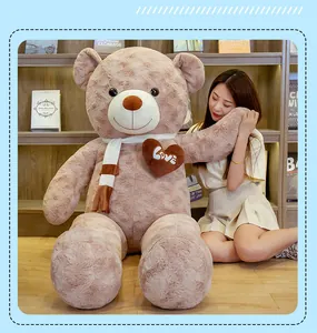 Giant plush teddy bear toy with scarf and heart, shown next to a person for scale